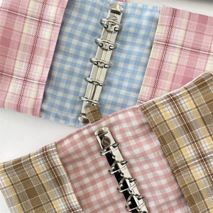 Détail de classeurs en tissu à carreaux avec 6 anneaux métalliques et coutures soignées