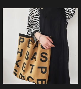 Detail of khaki canvas tote bag with black letter print and durable shoulder strap