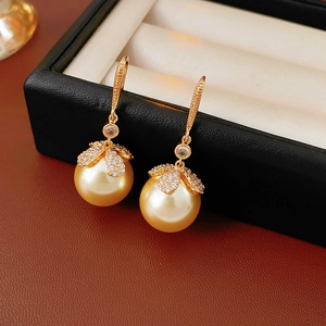 Vue macro de boucles d'oreilles fleur en or avec perles et pierres en zircon brillant