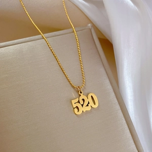 Detailed view of gold 520 pendant necklace on beige gift box with silk background