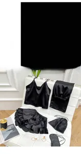 Macro detail of a 6-piece black satin sleepwear set with lace trim and heart accessory