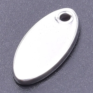 Macro shot of silver oval stainless steel pendant with hole on dark textured background