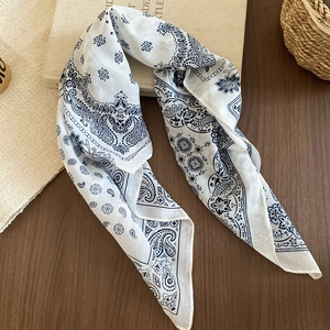 Close-up of retro paisley floral silk scarf with blue patterns on white fabric texture
