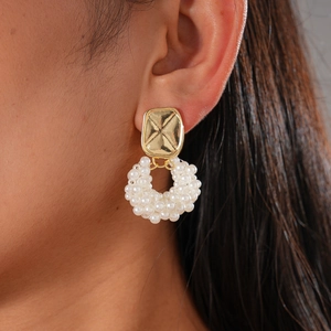 Detailed close-up of a vintage geometric gold earring with faux pearl circular accents