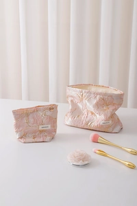 Detailed close-up of pink jacquard makeup bags with gold floral texture and brand label