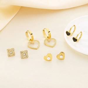 Élégant ensemble de boucles d'oreilles cœur en or avec perles sur fond de soie jaune