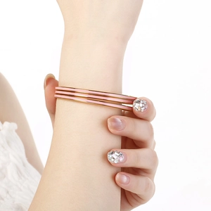 Three-piece set of thin gold stainless steel bangles with pink enamel insets on a wrist