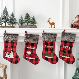 Lot de quatre chaussettes de Noël à carreaux rouges suspendues sur une cheminée blanche