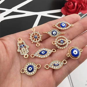 Macro view of gold evil eye hamsa hand and helm connectors for DIY jewelry making in palm