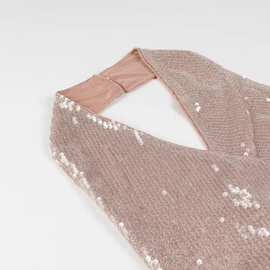 Detail of rose gold sequin halter neck with criss-cross design and shiny texture