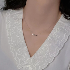 Close-up of sterling silver heart necklace with row of pendants on a female model