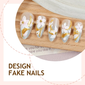 Almond shaped press-on nails with 3D white flowers and gold foil accents on wood