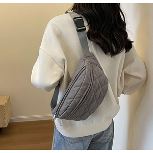 Rear view of model wearing a grey quilted nylon chest bag with adjustable strap