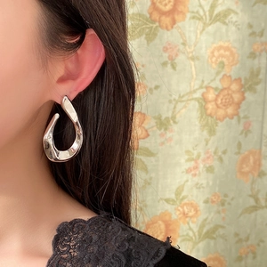 Close-up of polished silver twisted U-shaped earrings on model in French vintage style