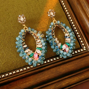 Gros plan de boucles d'oreilles bohèmes en perles bleues et cristaux colorés