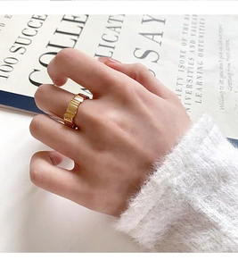 Close-up of gold plated wide band ring with vertical groove texture and zircon accents