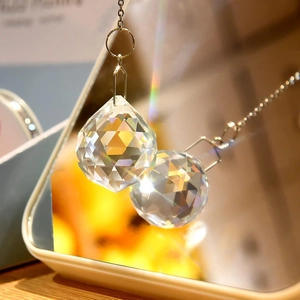 Faceted transparent crystal pendant balls reflecting rainbow light on a mirrored surface