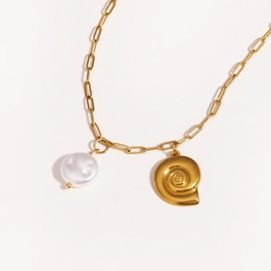 Detail of gold paperclip chain necklace with a white pearl and spiral seashell pendant