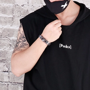 Detailed view of punk skull link bracelet on male wrist against an industrial brick wall