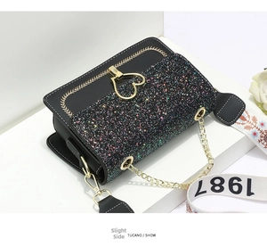 Detail of glitter flap handbag with golden heart clasp and embroidered floral strap