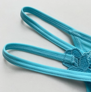 Close-up of lake blue lace lace thong featuring floral embroidery and elastic waistband