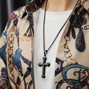 Close-up of a layered black cross necklace with engraved details worn by a male model