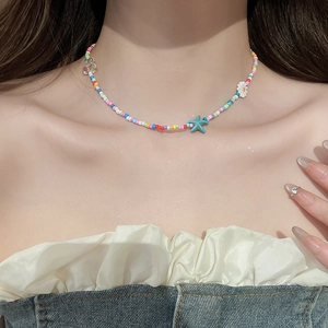 Close-up of beaded necklace featuring blue starfish and white flower charms on a model