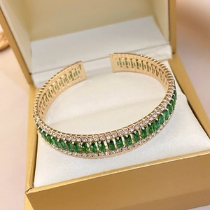Macro detail of emerald-green geometric bracelet with zircon accents in golden gift box