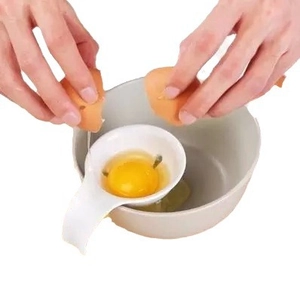 Separador de claras de huevo de plástico blanco con clip de silicona filtrando la yema