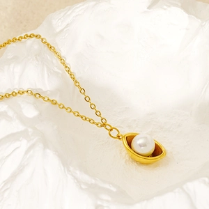 Vue macro du pendentif gousse dorée avec perle blanche sur chaîne fine en acier