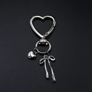 Close-up of silver steel keychain with heart clasp, solid heart charm and metal bow pendant