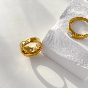 Detail of gold couple rings featuring one smooth band and one set with a clear gemstone