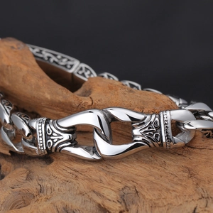 Vintage totem stainless steel bracelet with engraved texture on a rustic wooden stand