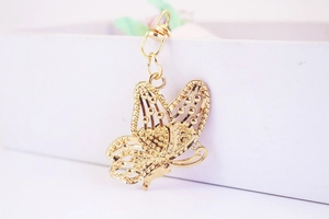Close-up of golden butterfly keychain with detailed hollow wings and lobster clasp