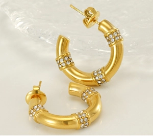 Macro view of gold-plated C-shaped bamboo earrings with micro-pave crystal accents