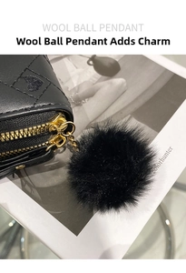 Detail of quilted leather wallet with dual gold zippers and a black wool ball pendant