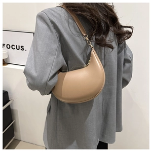 Model wearing a khaki crescent-shaped underarm bag with a grey blazer for a chic look