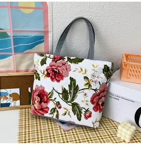 Detail of canvas tote bag featuring large vintage red rose print and grey handles