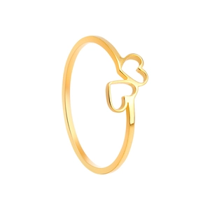Gros plan d'une bague dorée avec un design à double cœur évidé sur un fond blanc neutre