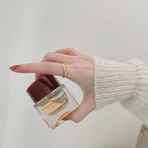 Detail of artistic gold irregular ring with minimalist hollow curves on a model finger