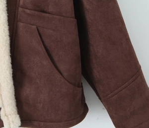 Détail de la veste en daim marron foncé avec doublure en laine crème et poches latérales