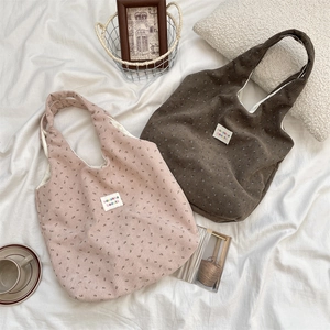 Detail of floral corduroy tote bags in pink and brown with branded woven labels