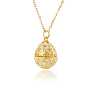 Detailed close-up of golden egg pendant with white enamel and hollow floral patterns
