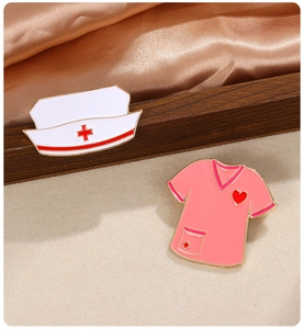 Detailed close-up of nurse hat and pink uniform enamel pins on a silk background