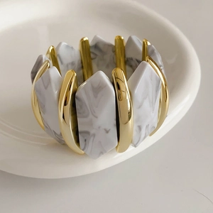 Détail de la texture marbre blanc et de l'élément en métal doré sur le bracelet élastique