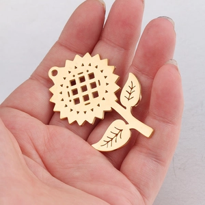Golden stainless steel sunflower pendant with leaf detail shown in a hand-held view