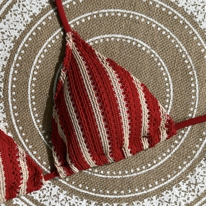 Detailed view of red and beige striped crochet bikini top with textured knit fabric