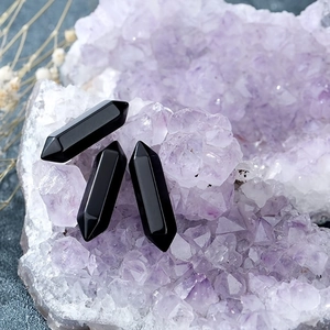 Three black hexagonal crystal pillars set against a cluster of purple quartz druzy