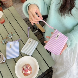 Detailed shot of small striped canvas pouches in pink, blue and green with zipper