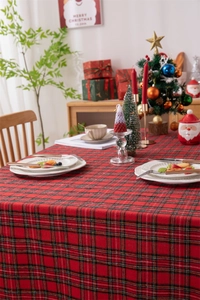 Festive red plaid Christmas tablecloth with decorative fringe in a cozy holiday setting